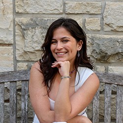 Tenley Decker sitting on a bench outside a K-State campus building
